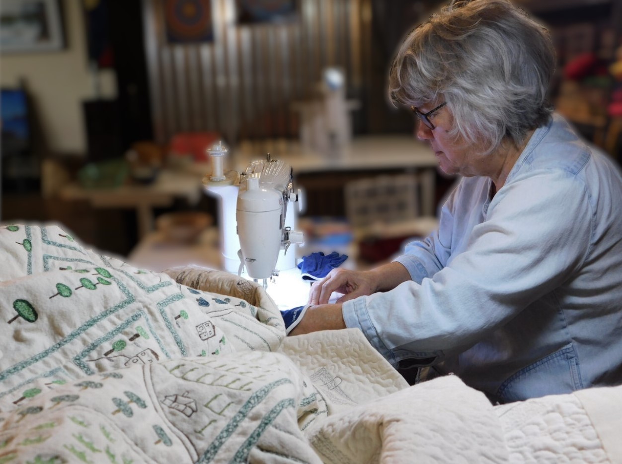 Photo of Cathy Fussell working on the quilt “The Margravate of Azilia” in her studio.